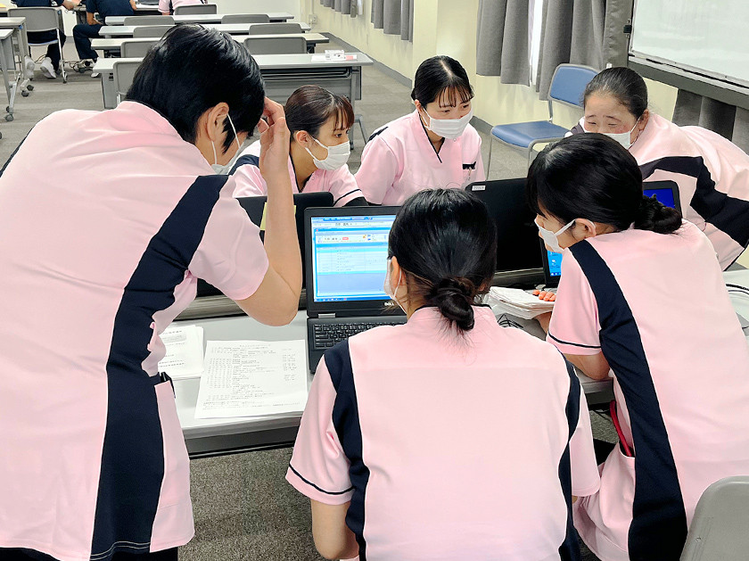 写真：6名の看護師がパソコンを囲んで相談している様子
