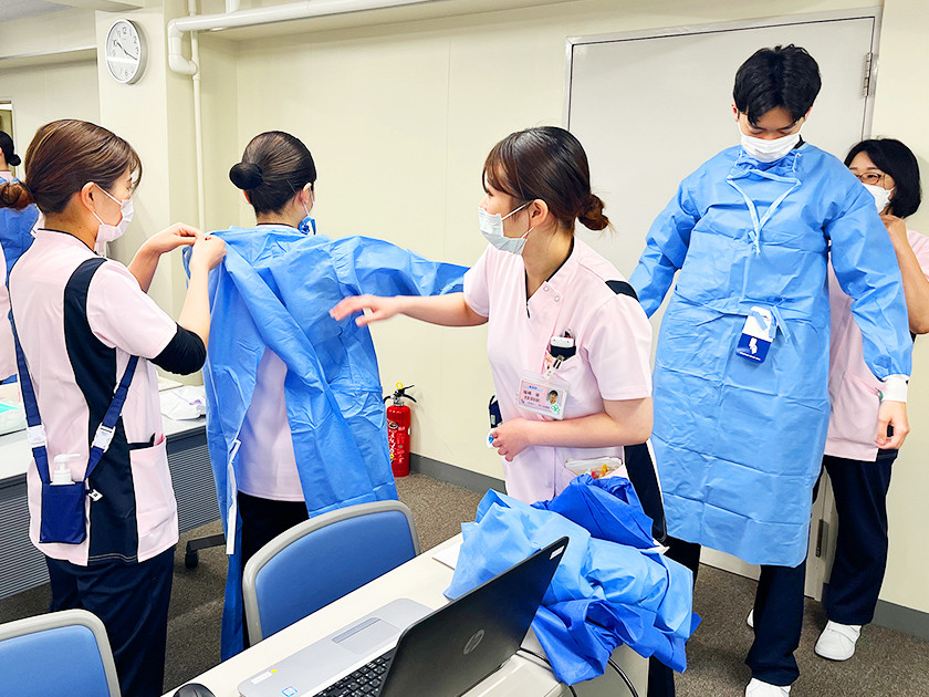 写真：他の看護師に手術着を着せてもらっている様子