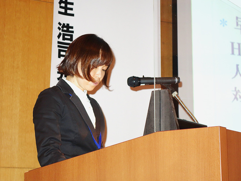 写真：医学総会にて壇上で発表を行なっている女性