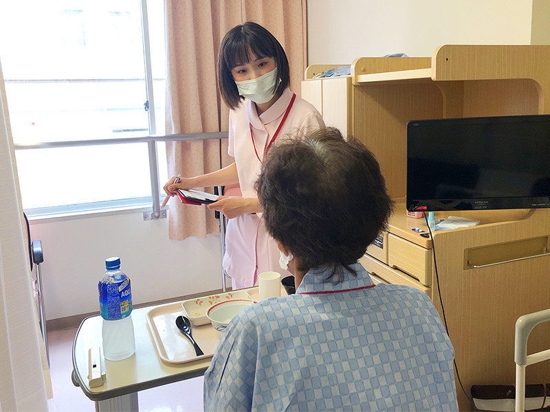写真：食事の時間や回診で入院患者さんのベットサイドへ訪問している風景