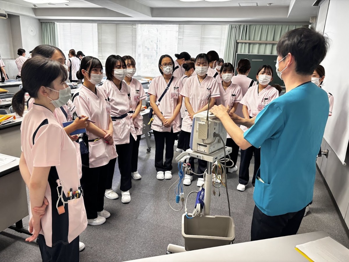 写真：ベッドを囲んで説明を受けている様子