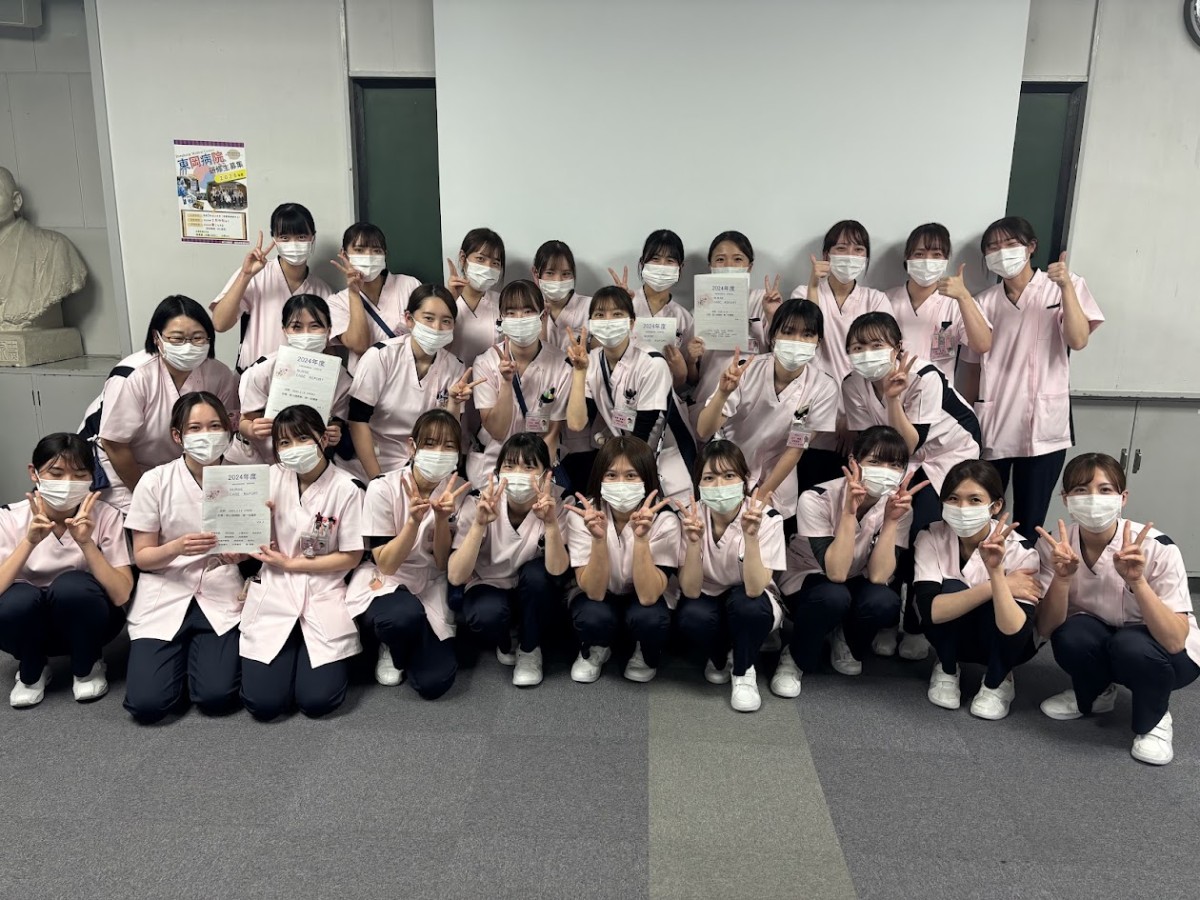 写真：人物模型をベッドに横たえて、作業について説明を受けている様子