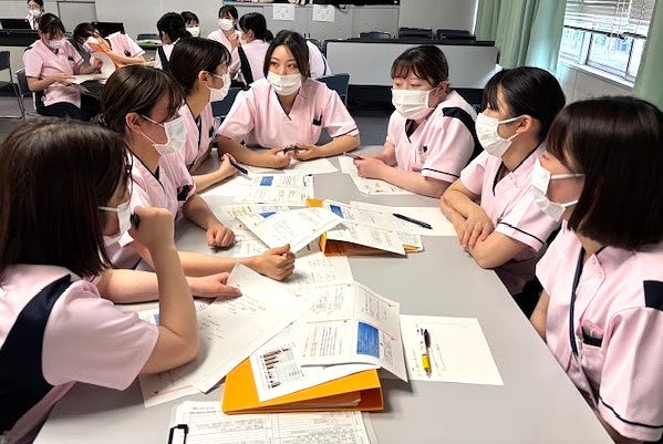 写真：他の看護師に手術着を着せてもらっている様子